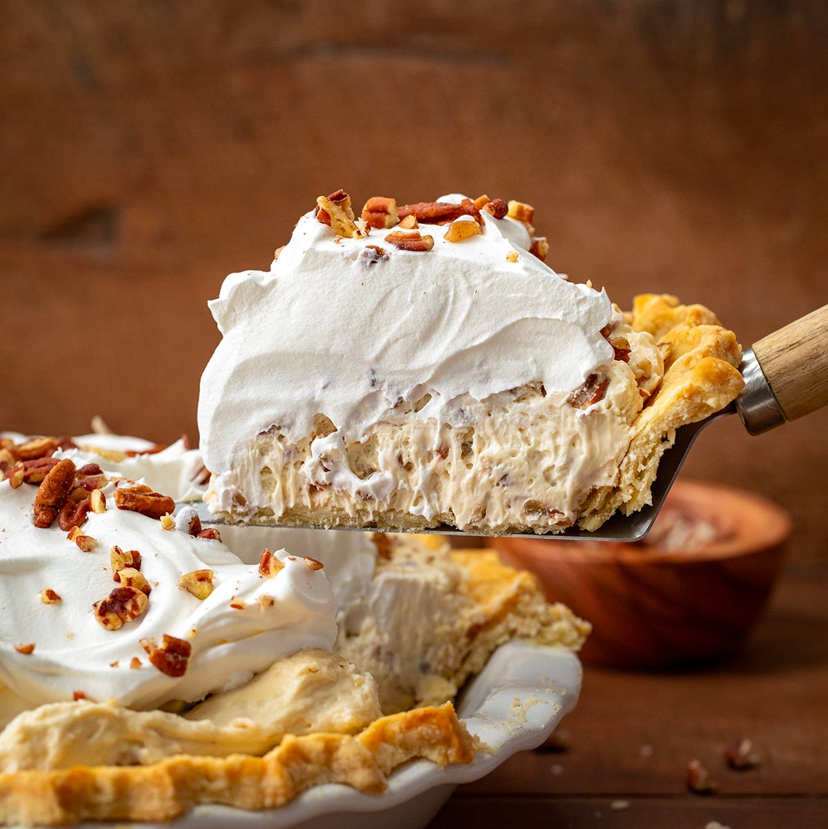 Spatula picking up a piece of Pecan Cream Pie from the pie plate.