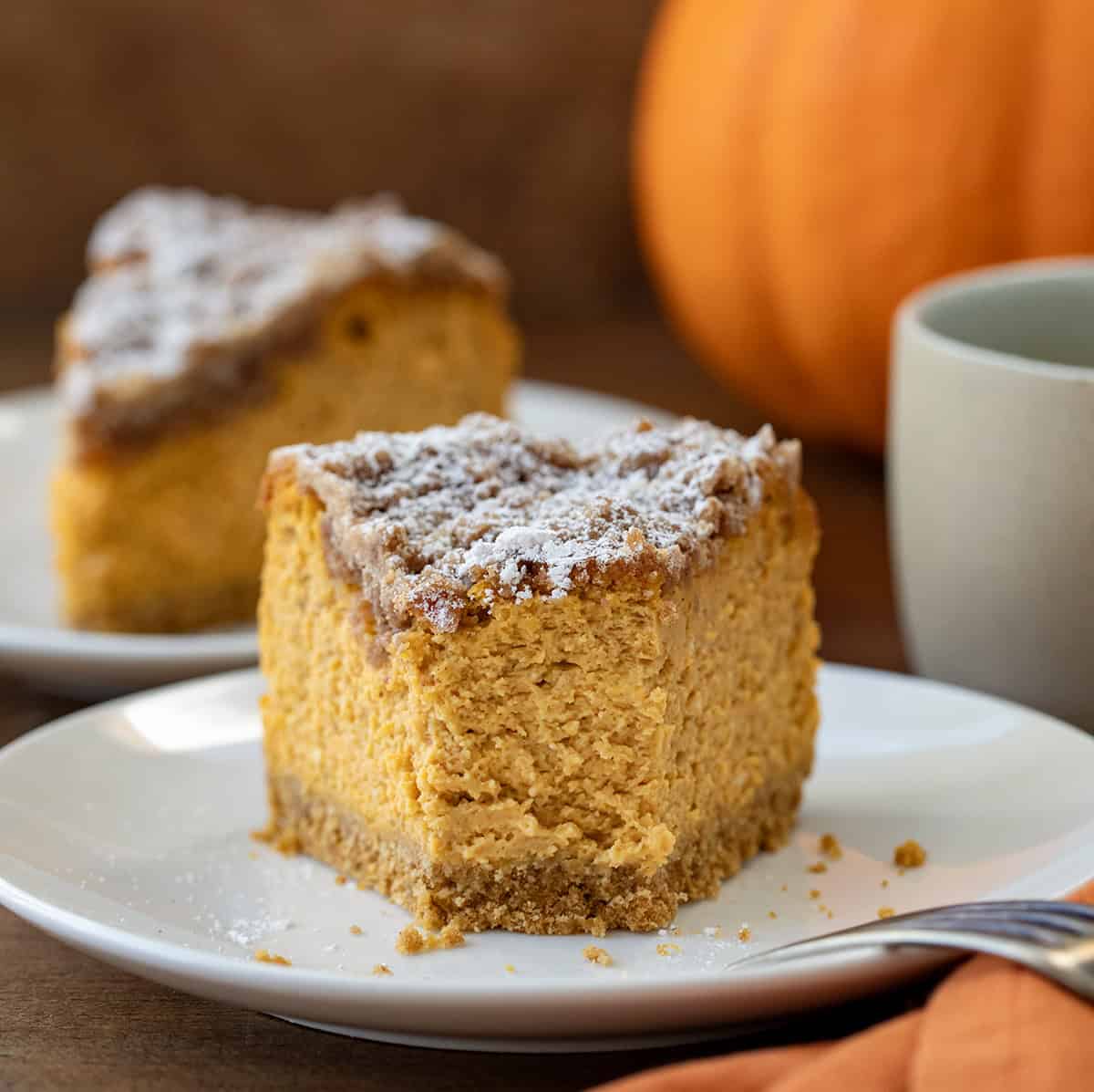 Piece of Pumpkin Crumble Cheesecake on a white plate with a bite taken out.