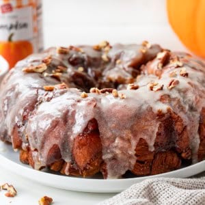 Whole Pumpkin Monkey Bread on a white platter with pumpkin puree in the background.