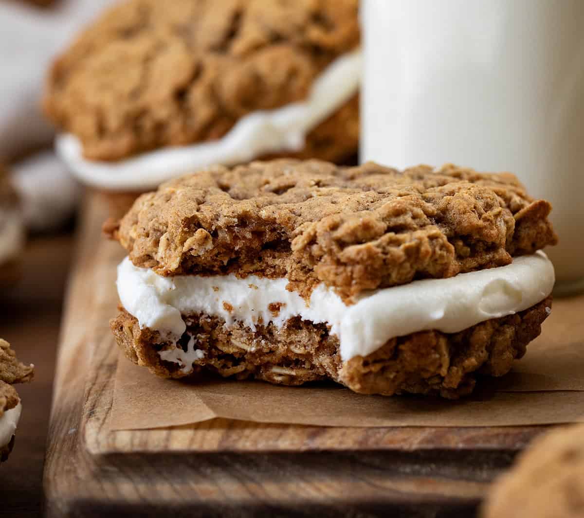 Bit into Pumpkin Oatmeal Cream Pie on a wooden cutting board with milk in the background.