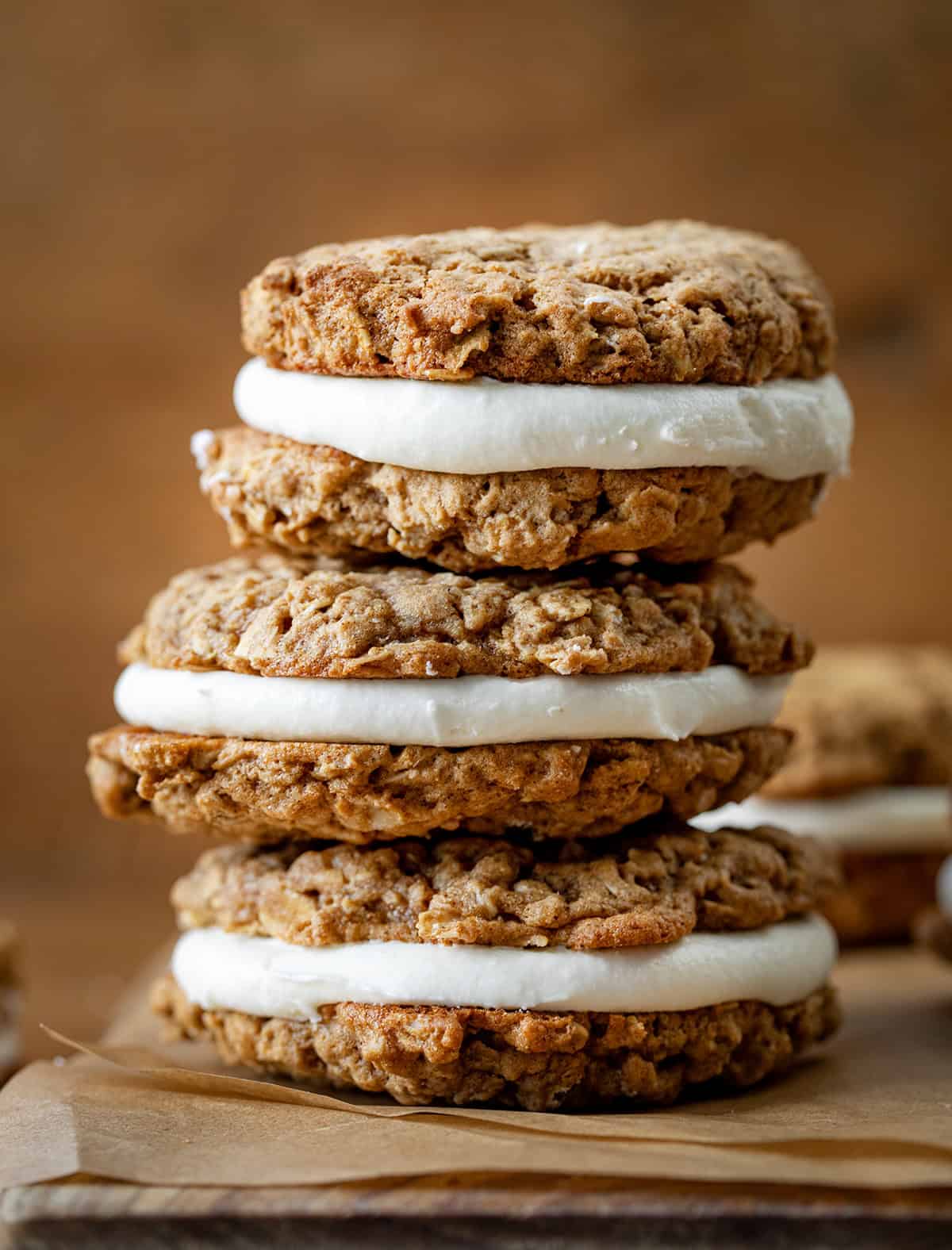 Stack of Pumpkin Oatmeal Cream Pie cookies on a cutting board on a wooden table.