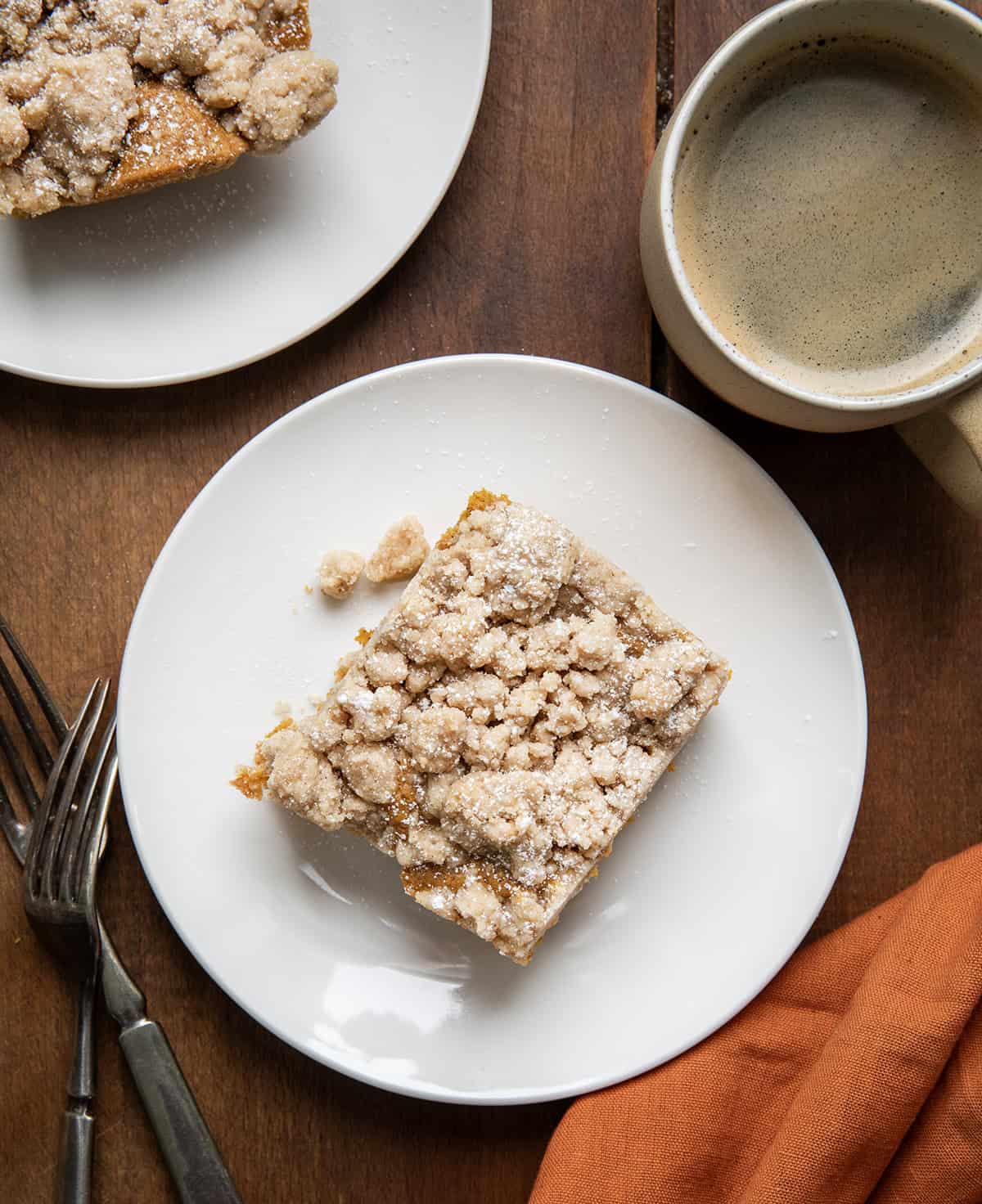 Pieces of Pumpkin Spice Coffee Cake on white plates on a wooden table from overhead.