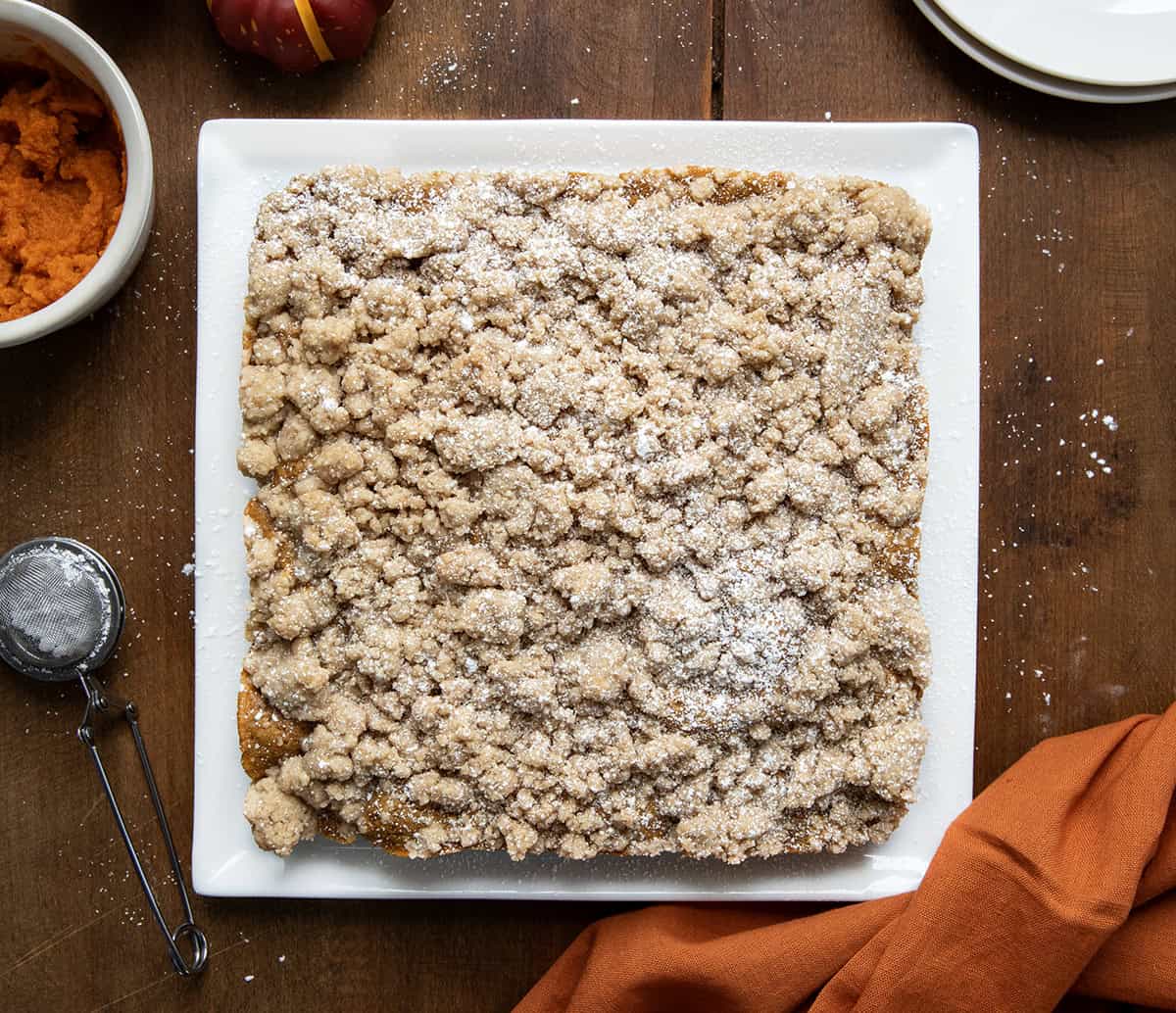 Whole Pumpkin Spice Coffee Cake on a white platter on a wooden table from overhead.