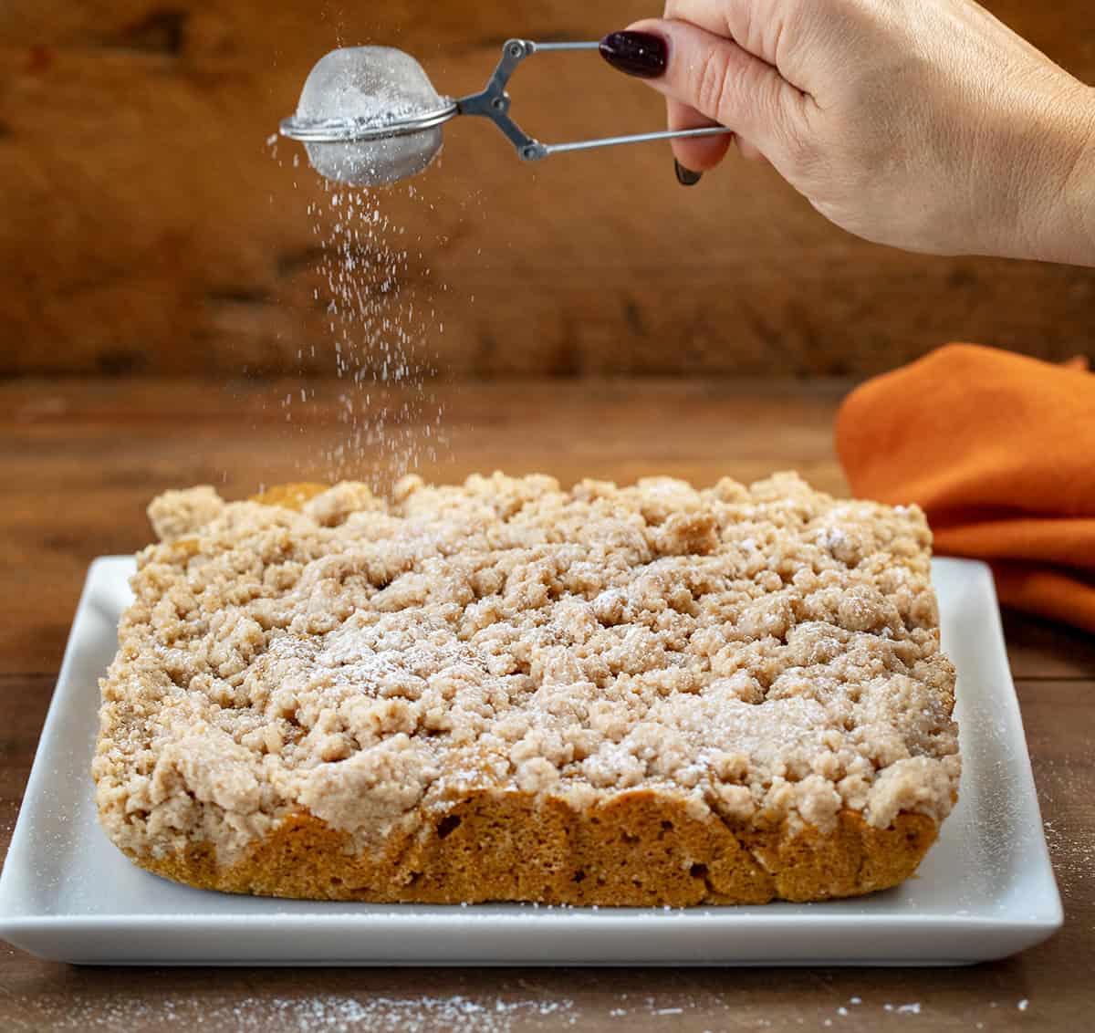 Dusting confectioners sugar over Pumpkin Spice Coffee Cake.