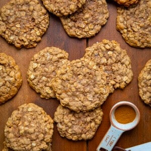 Pumpkin Spice Oatmeal Cookies on a wooden table with pumpkin spice from overhead.