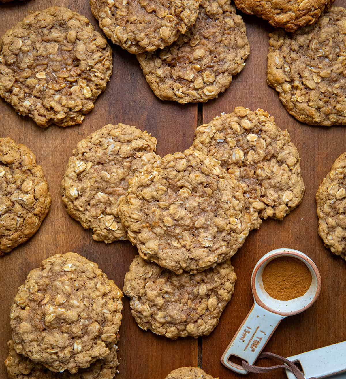 Pumpkin Spice Oatmeal Cookies on a wooden table with pumpkin spice from overhead.