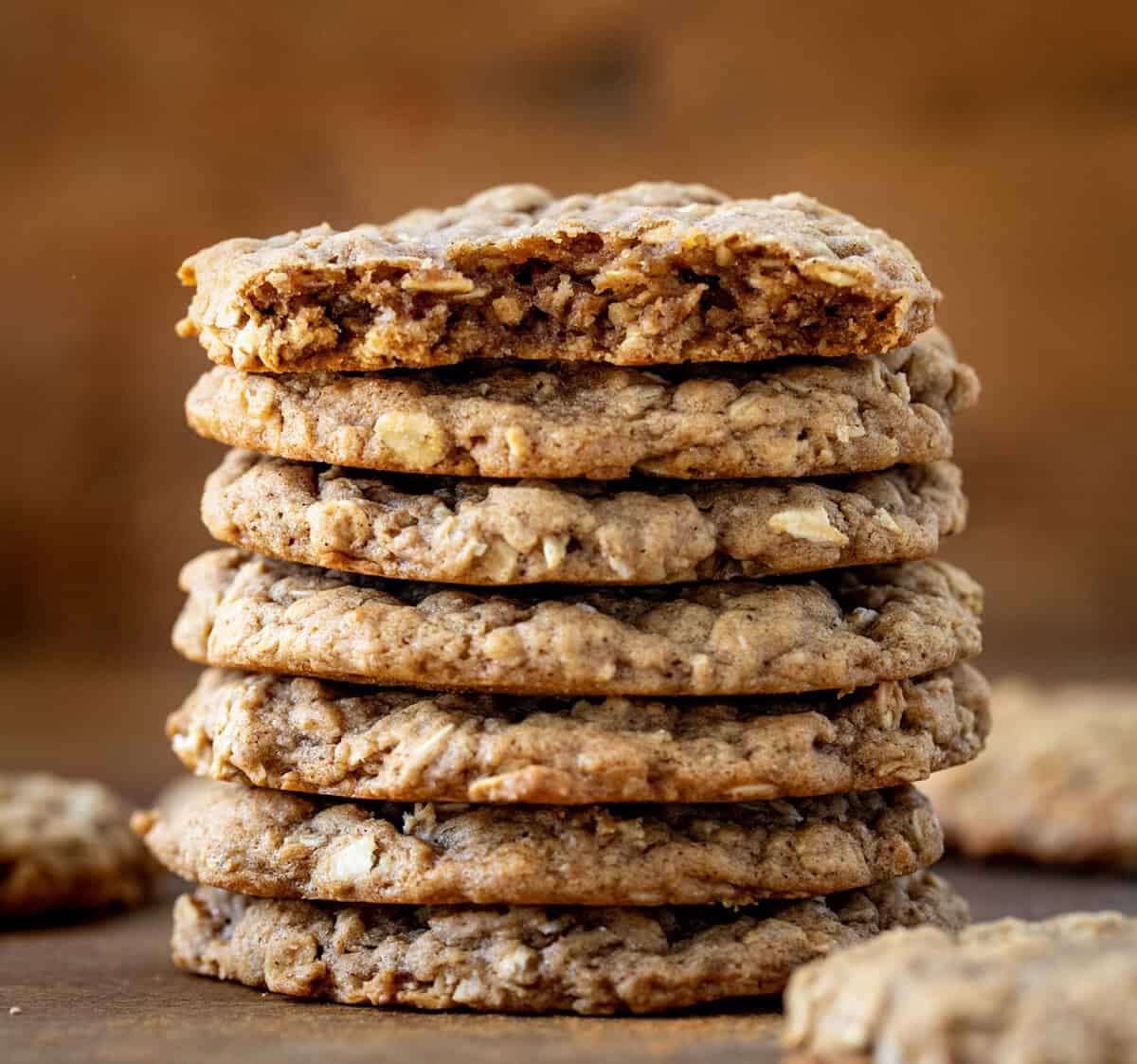 Stack of Pumpkin Spice Oatmeal Cookies on a wooden table with top cookie broken in half.