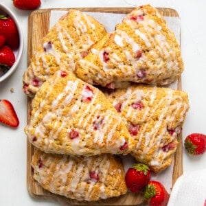 Strawberries and Cream Scones on a wooden cutting board on a white table from overhead.