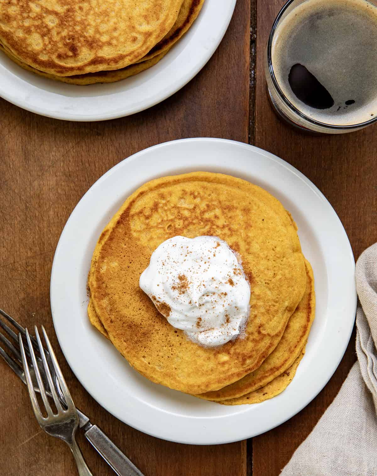 White plates on a wooden table with Sweet Potato Pancakes on them from overhead.