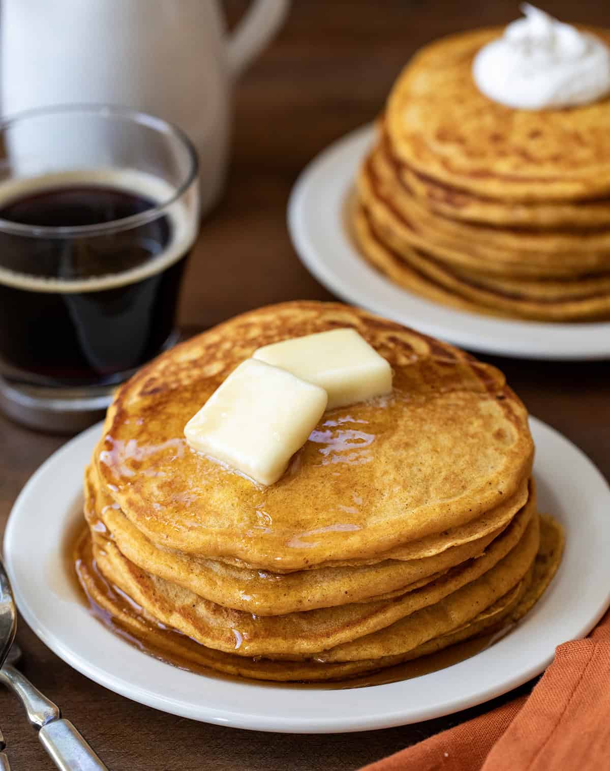 Plates with big stacks of Sweet Potato Pancakes topped with melting butter.