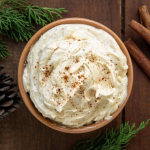 Bowl of Whipped Gingerbread Butter on a wooden table from overhead with cinnamon sticks.