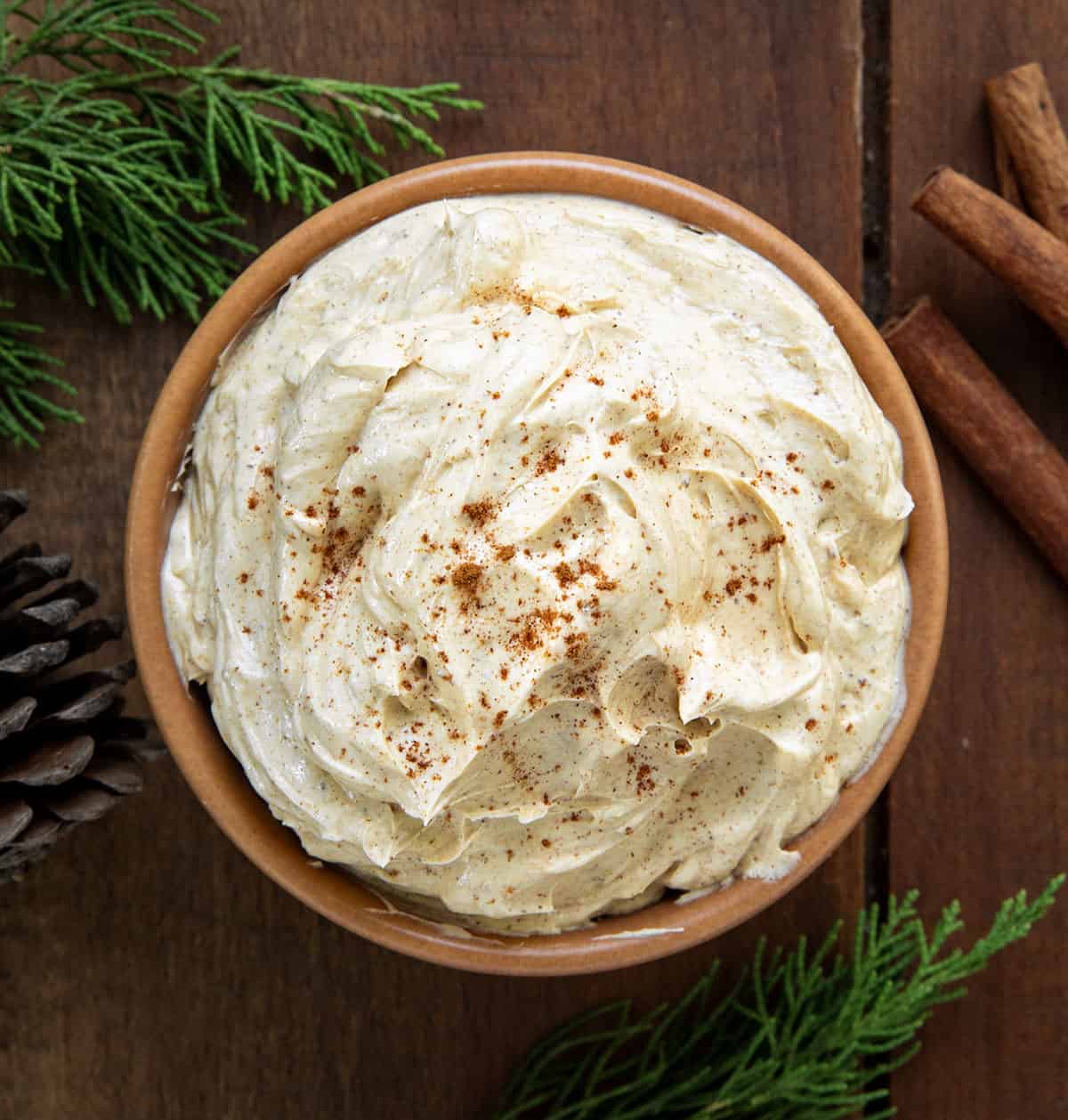 Bowl of Whipped Gingerbread Butter on a wooden table from overhead with cinnamon sticks.