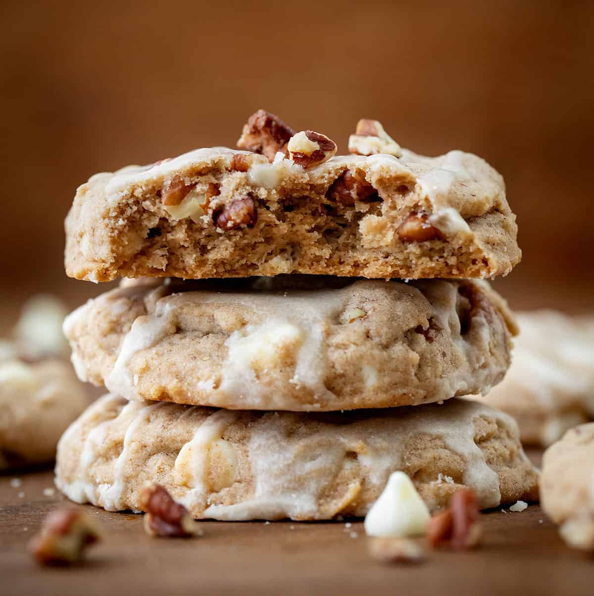 Stack of White Chocolate Maple Pecan Cookies with top cookie broken in half showing inside texture.