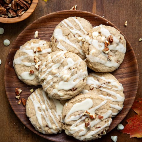 White Chocolate Maple Pecan Cookies on a wooden plate on a wooden table.