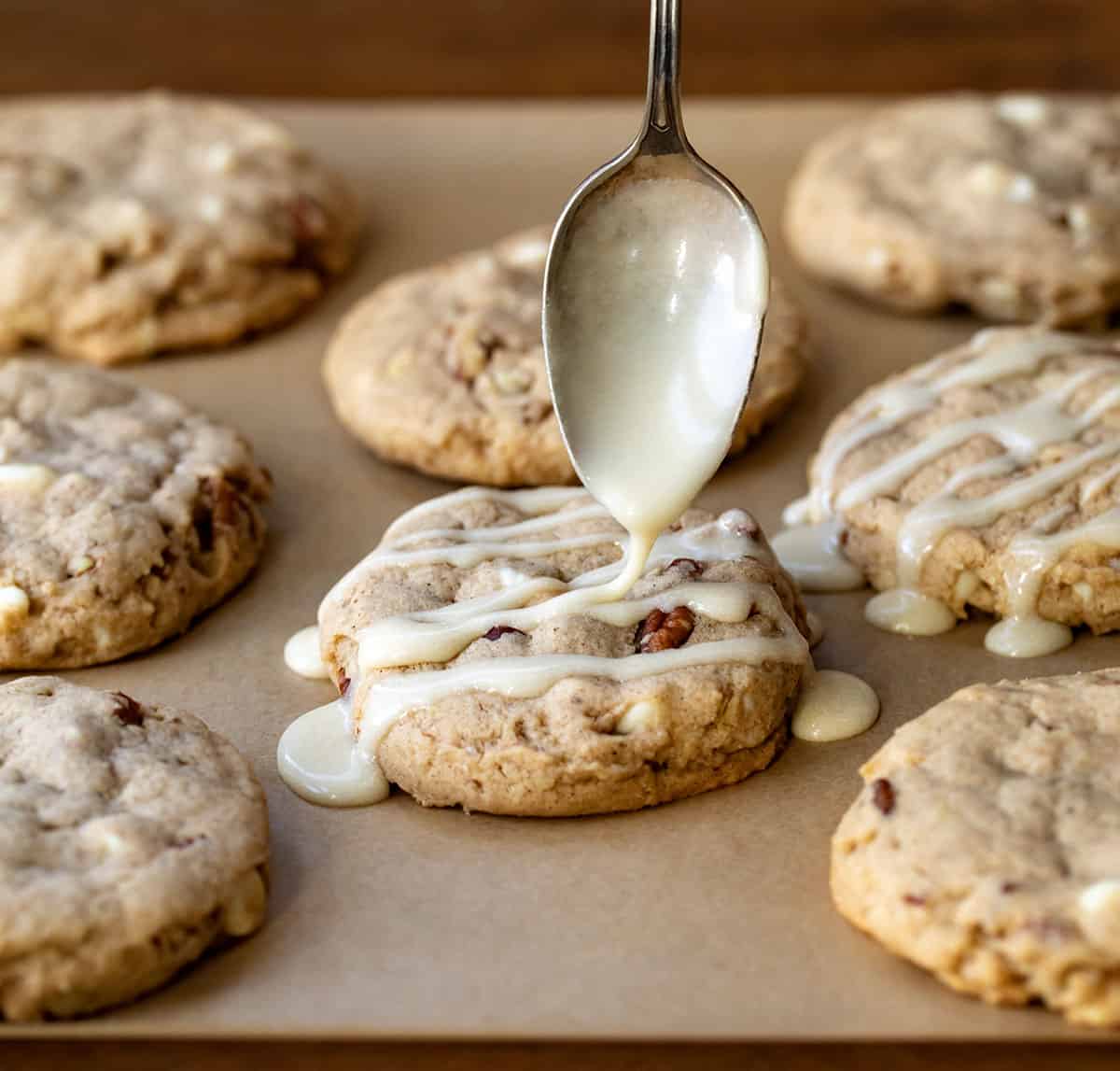 Drizzling glaze over White Chocolate Maple Pecan Cookies.