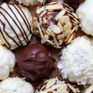 Almond Joy Truffles on a piece of parchment paper very close together and very close to the truffles.