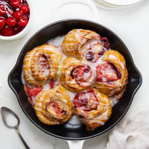 Skillet of Cherry Cheesecake Pinwheels on a white table from overhead.