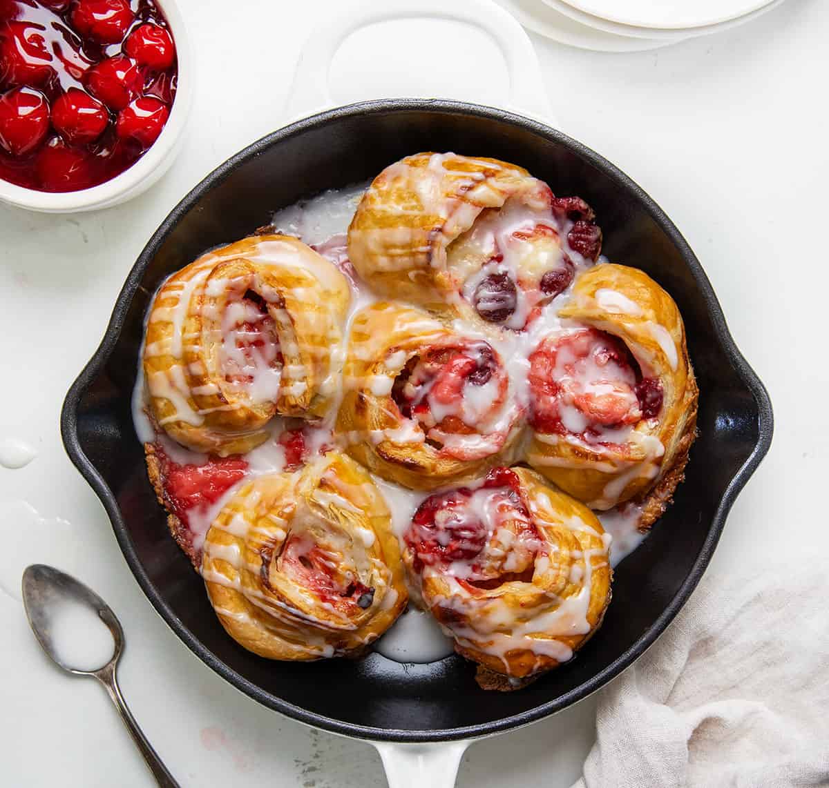 Skillet of Cherry Cheesecake Pinwheels on a white table from overhead.