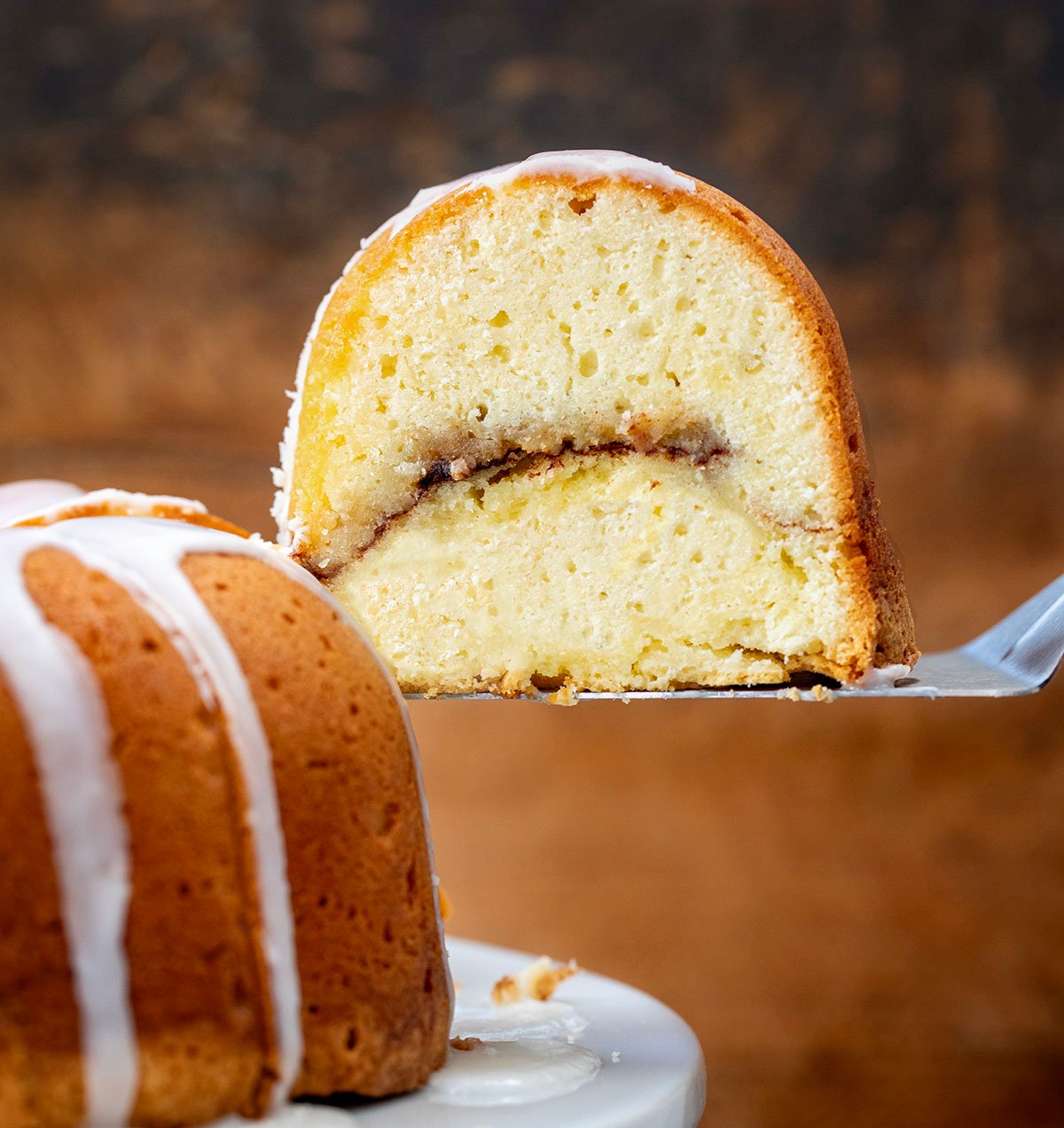 Picking up a piece of Cinnamon Swirl Bundt Cake from cake stand.