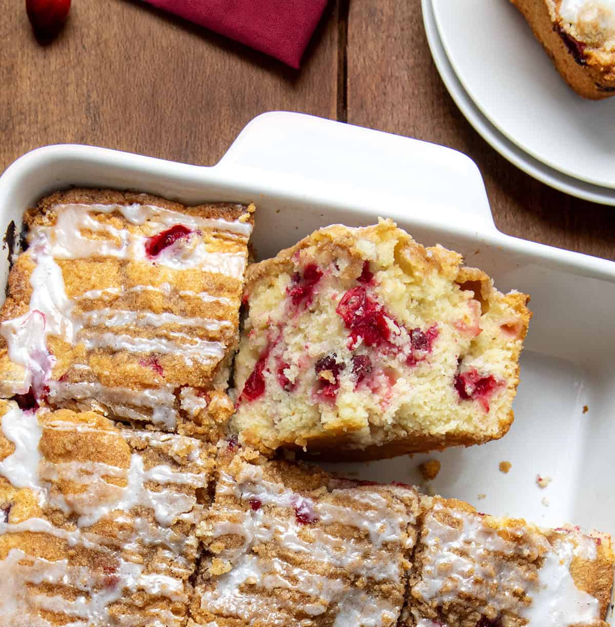 Cranberry Coffee Cake in a pan with the pieces cut and one piece on its side.