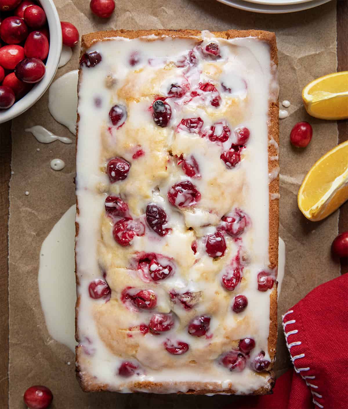 Glaze covered Cranberry Orange Loaf on a wooden table from overhead.