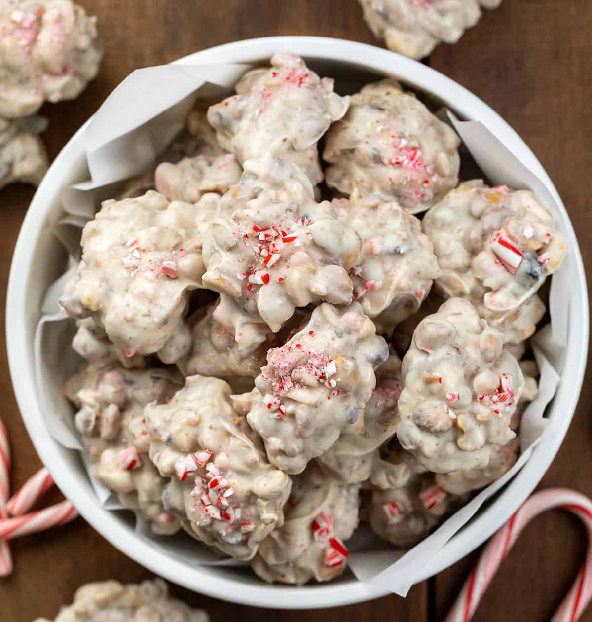 Bowl of Crockpot Christmas Candy on a wooden table with peppermint candy cans from overhead.