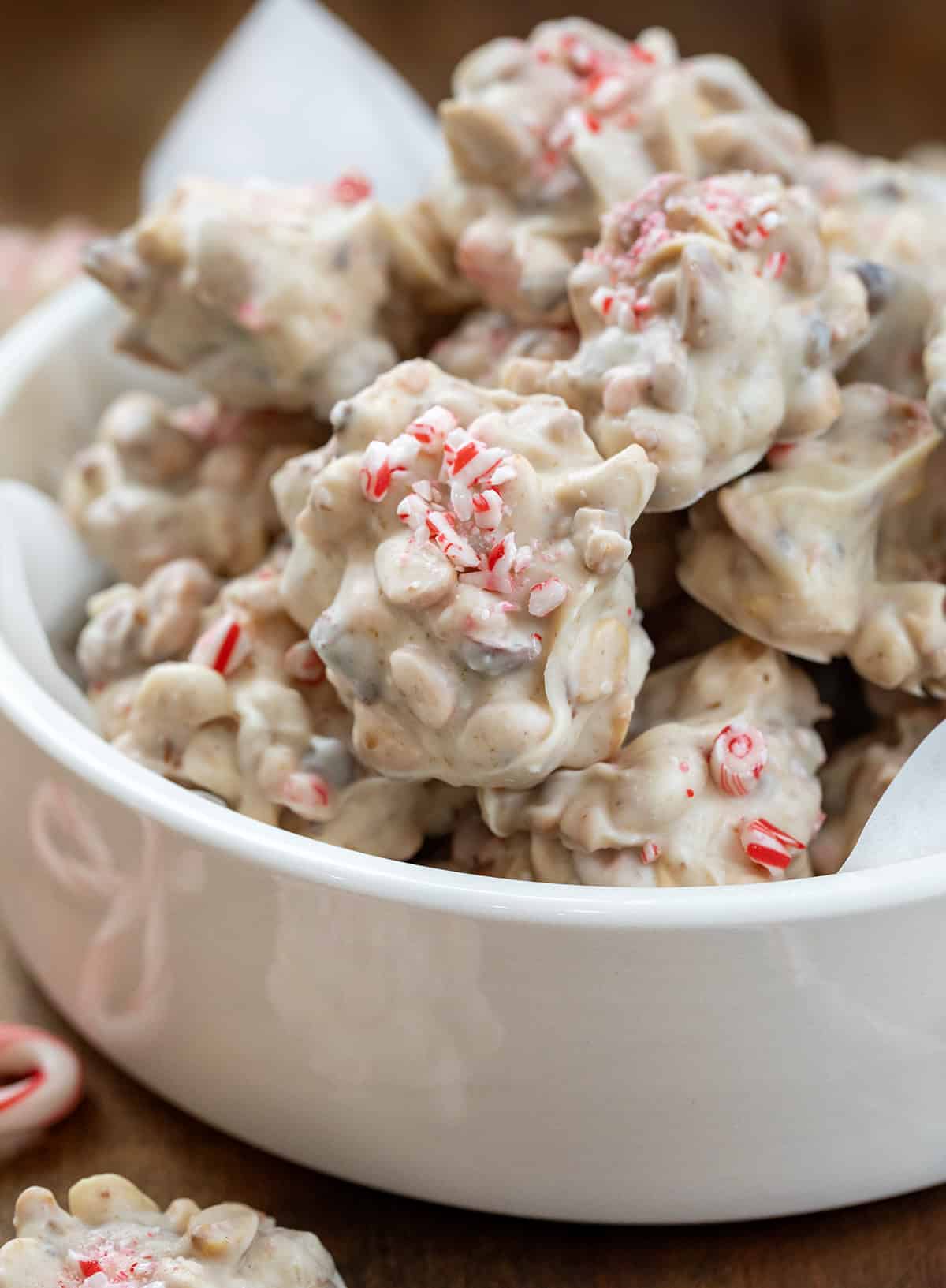 Bowl of Crockpot Christmas Candy surrounded by peppermint candy canes.