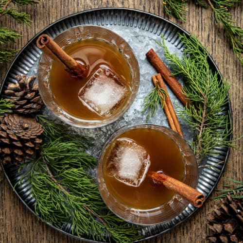 Two Gingerbread Old Fashioned's on a tray on a wooden table from overhead.