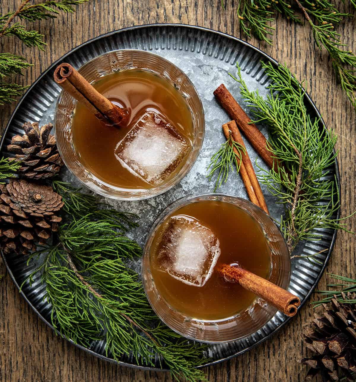 Two Gingerbread Old Fashioned's on a tray on a wooden table from overhead.