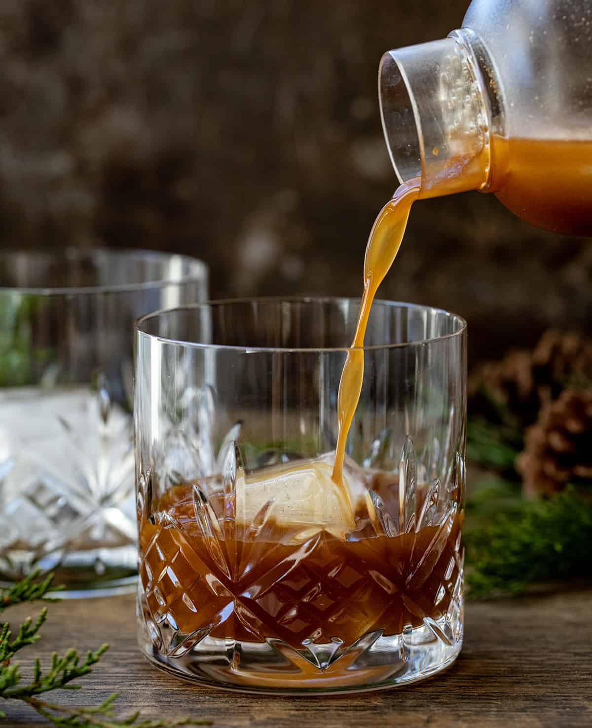 Pouring Gingerbread Old Fashioned into a glass with ice.