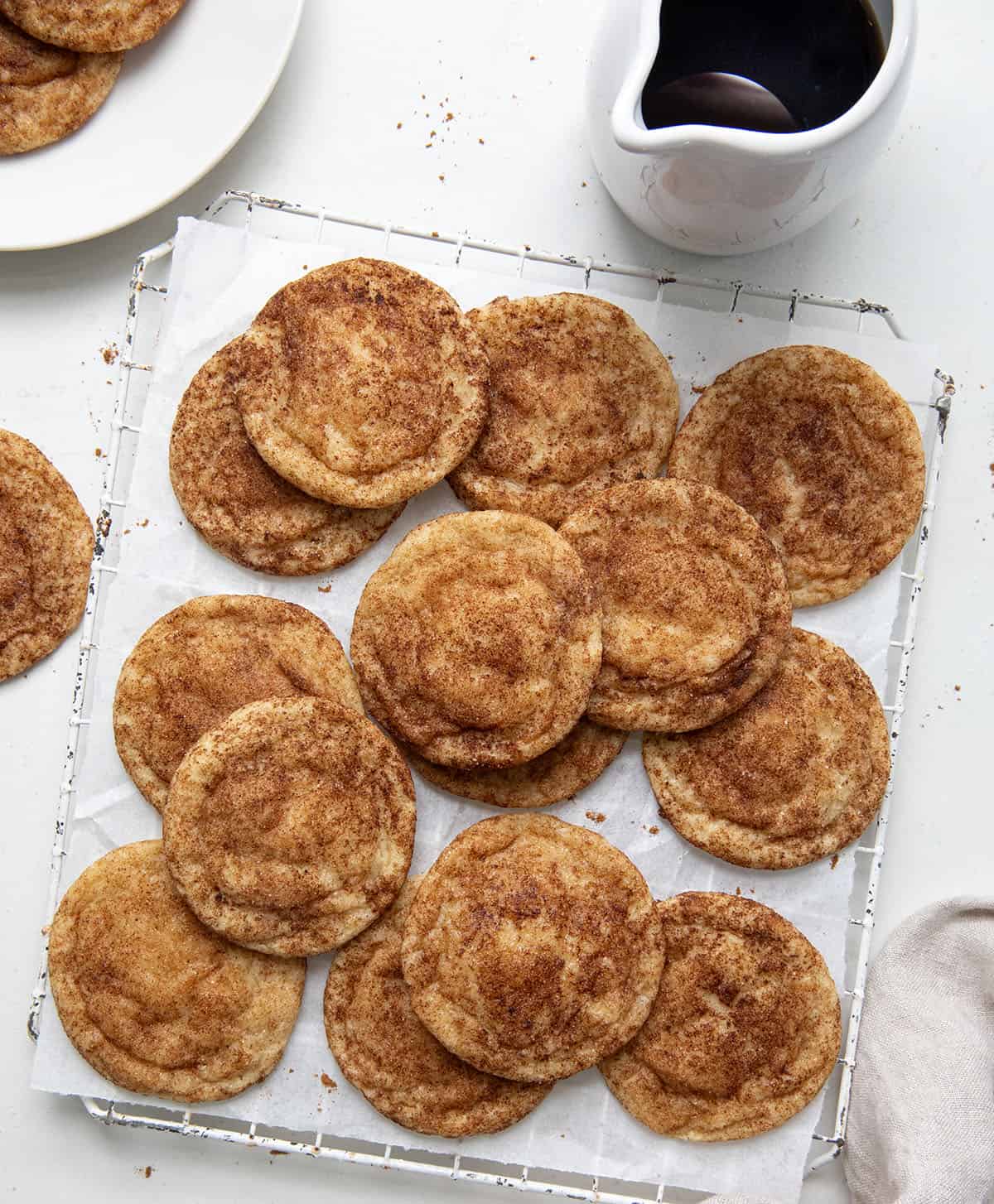 White wire rack with Maple Snickerdoodles on it and a container of maple syrup. 