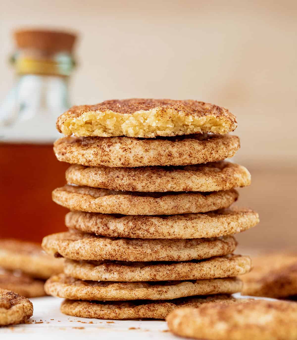 Stack of Maple Snickerdoodles with a bottle of maple syrup in the background.