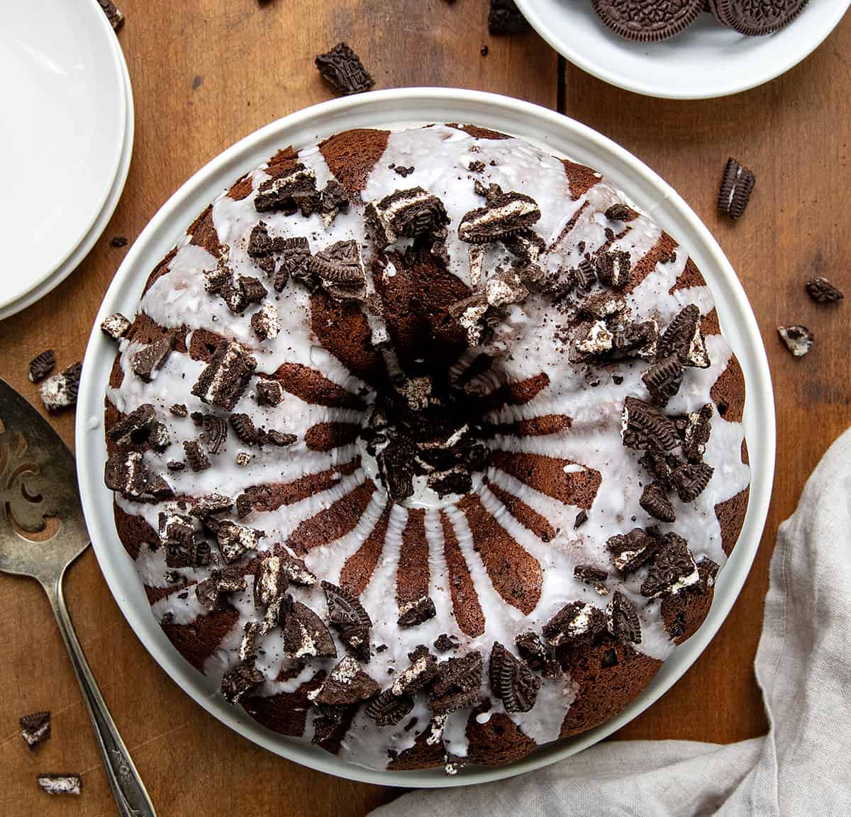 Oreo Bundt Cake on a white cake plate on a wooden table from overhead.