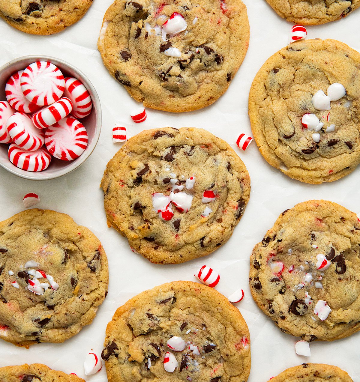 Peppermint Chocolate Chip Cookies on a white table with a bowl of peppermint candies.