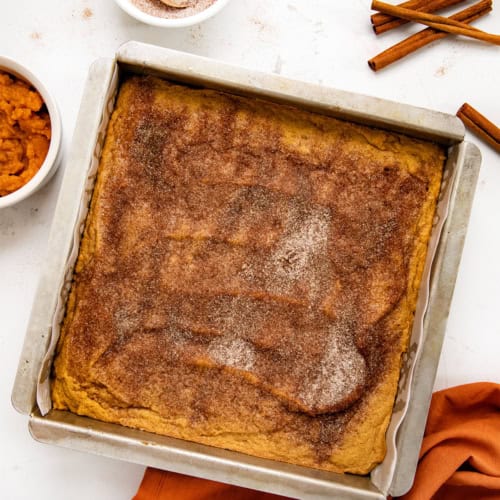 Pan of Pumpkin Snickerdoodle Brownies on a white counter with an orange towel.