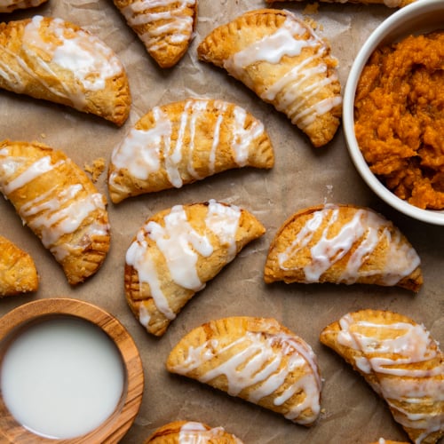 Sweet Potato Hand Pies on parchment paper with glaze and sweet potato filling.