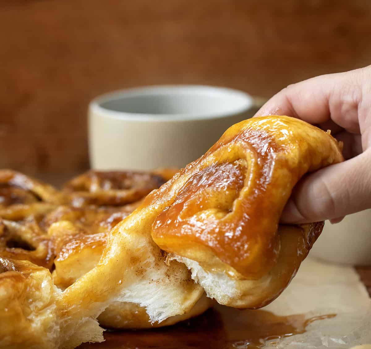 Hand picking up a Butterscotch Caramel Roll.