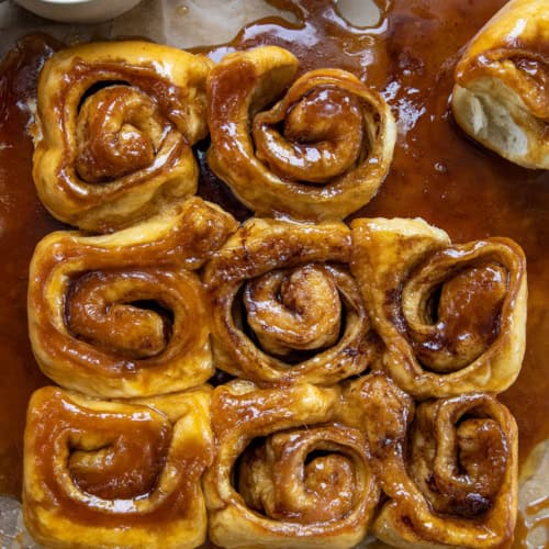 Butterscotch Caramel Rolls on parchment paper on a wooden table from overhead.