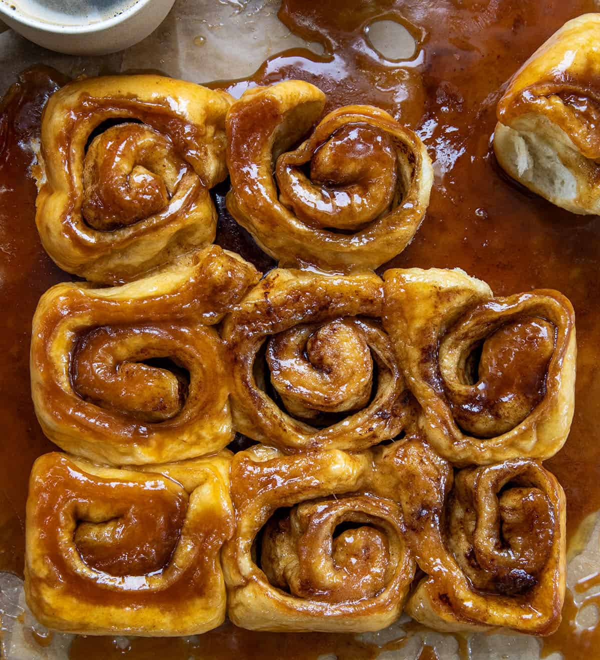 Butterscotch Caramel Rolls on parchment paper on a wooden table from overhead.