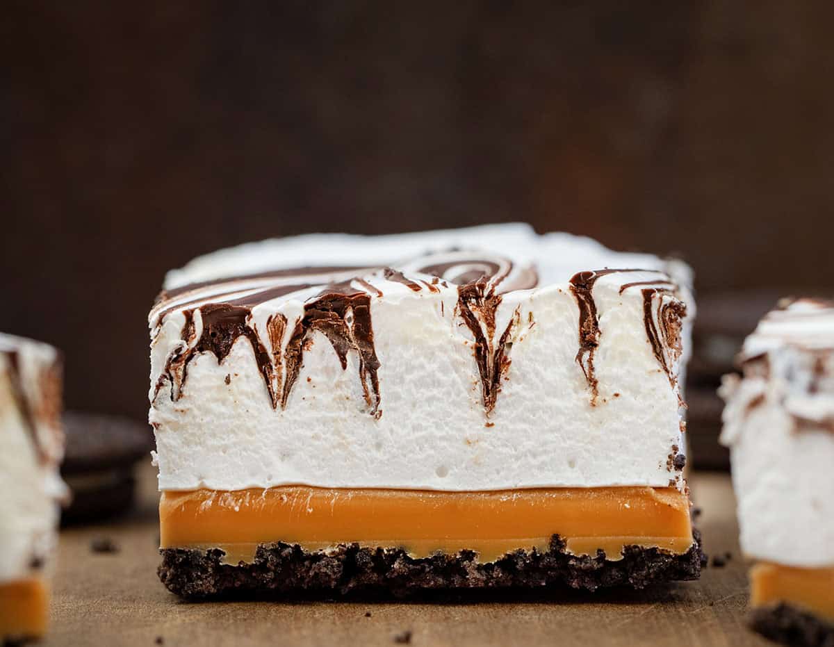 Close up of a cut Caramel Marshmallow Bars showing the oreo crust, caramel, and marshmallow chocolate layer.