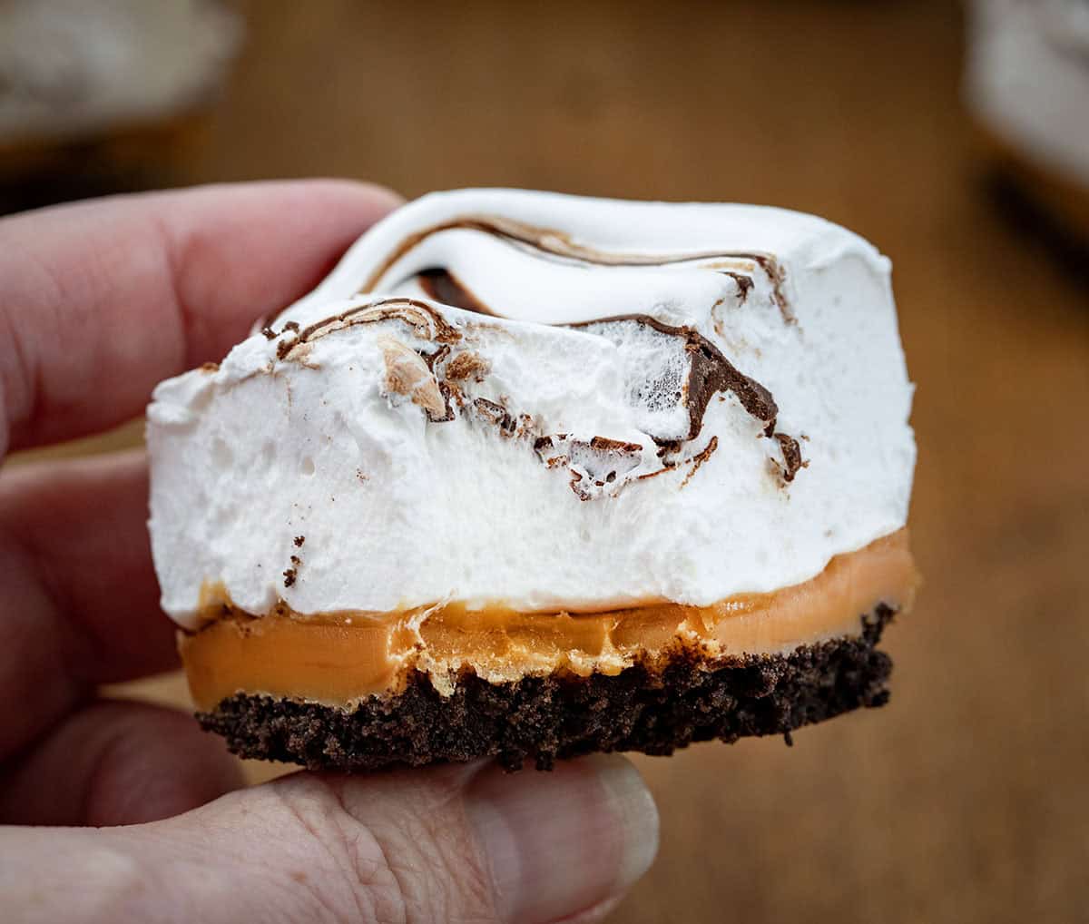 Hand holding a Caramel Marshmallow Bars that has a bite taken out of it.