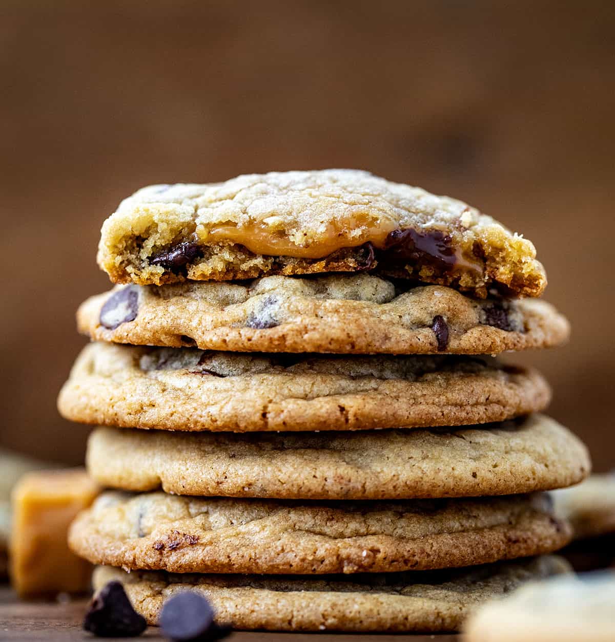 Stack of Caramel Stuffed Chocolate Chip Cookies with top cookie halved showing the inside caramel.