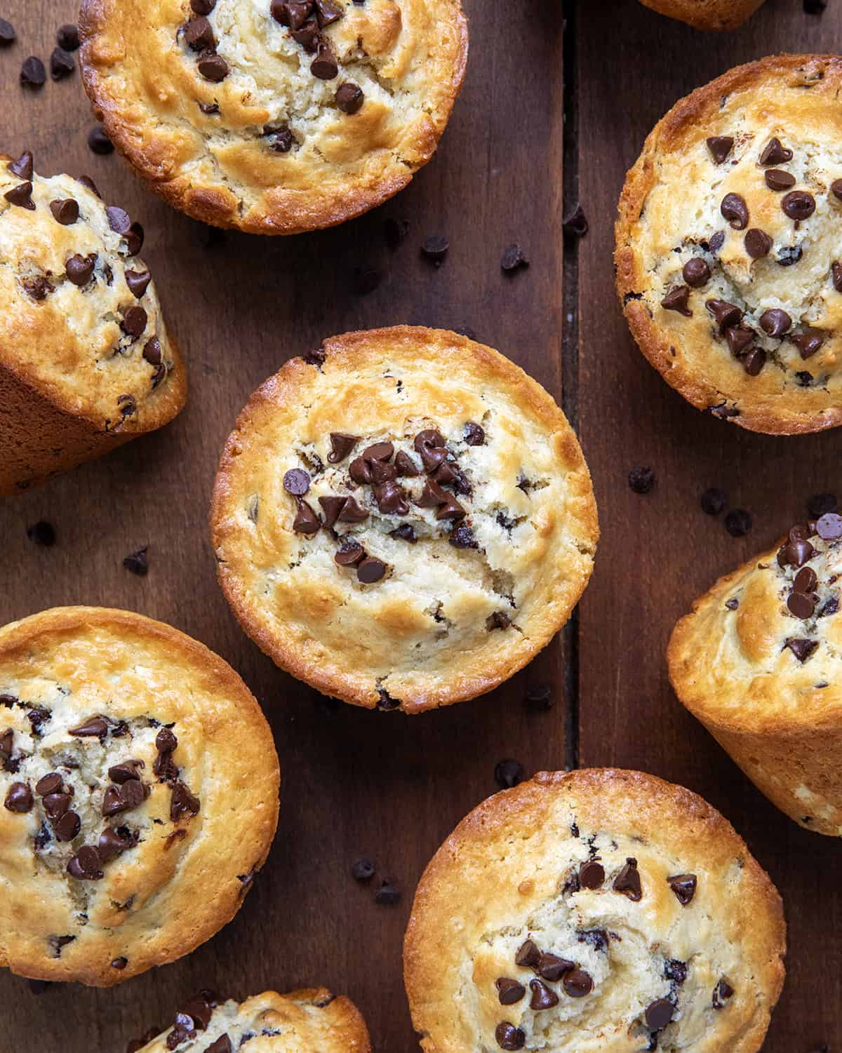 Bakery Style Chocolate Chip Muffins on a wooden table from overhead.