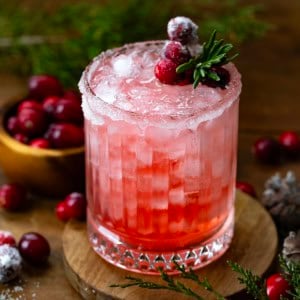 Glass of Christmas Gin Fizz on a wooden table with cranberries.