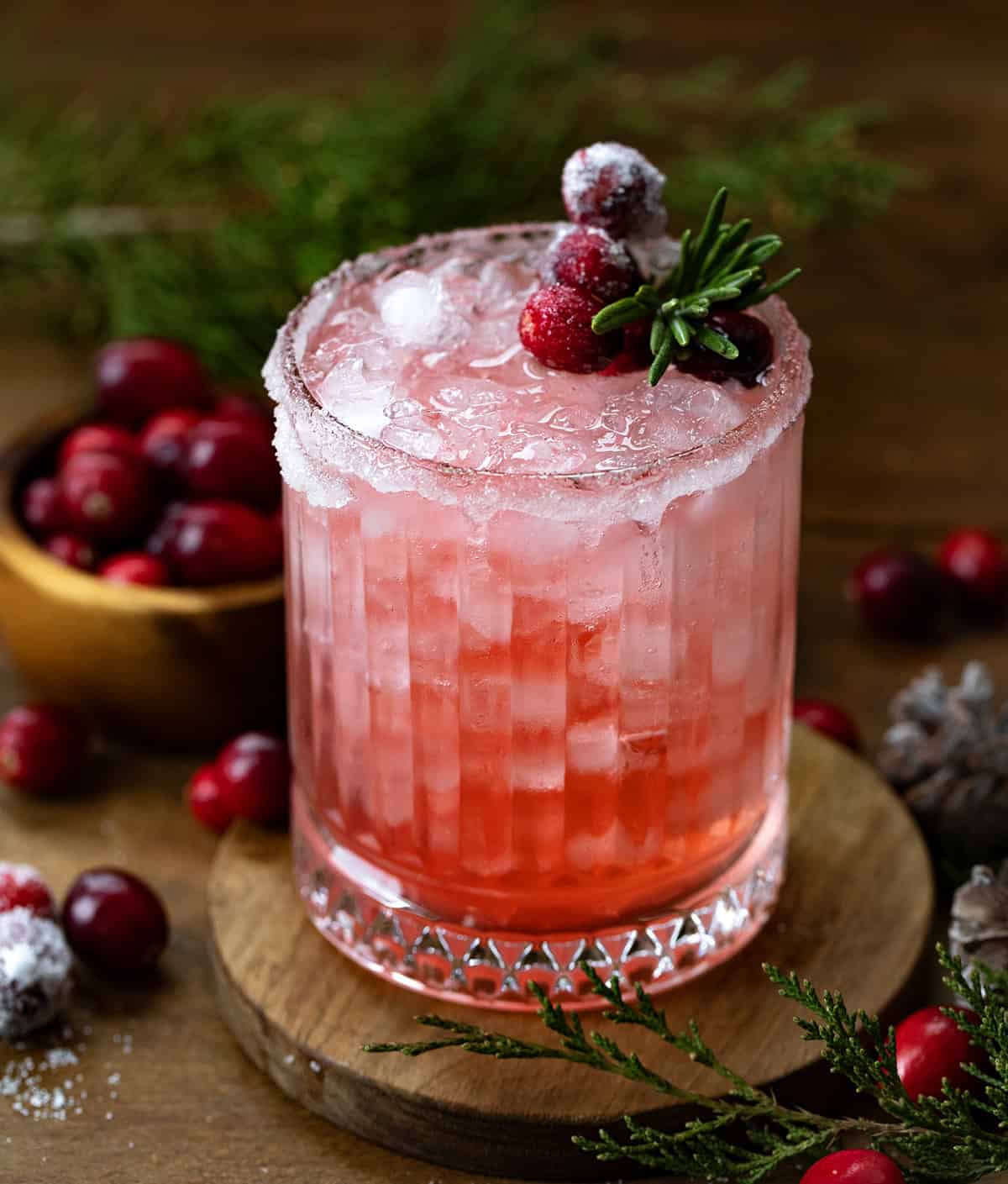 Glass of Christmas Gin Fizz on a wooden table with cranberries.