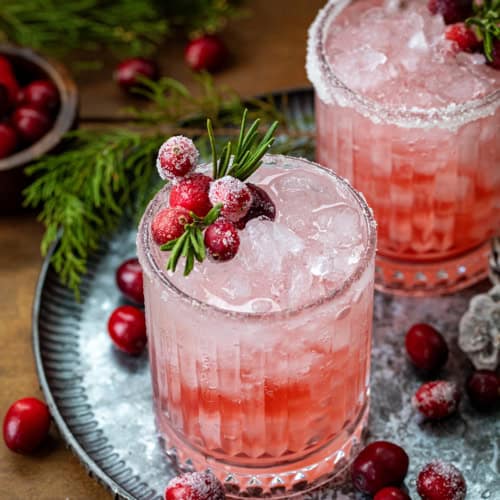 Glasses of Christmas Gin Fizz on a tray on a wooden table.