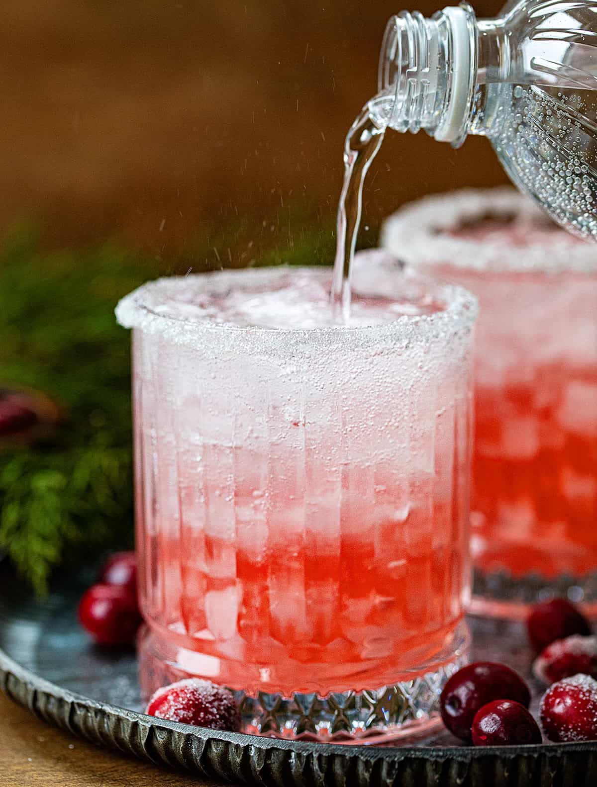 Pouring the fizz into a glass to make a Christmas Gin Fizz.