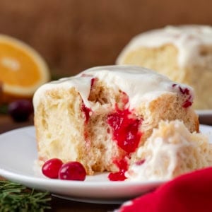 Bit into Cranberry Orange Sweet Roll on a white plate close up showing inside raspberry glaze.