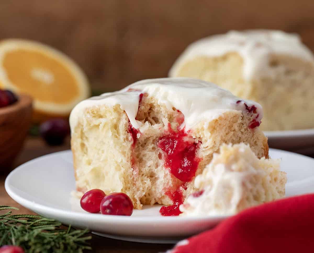 Bit into Cranberry Orange Sweet Roll on a white plate close up showing inside raspberry glaze.