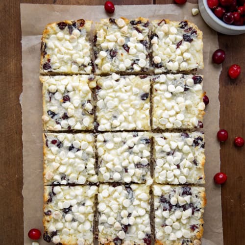 Cranberry White Chocolate Magic Bars cut into square bars on a wooden table from overhead.